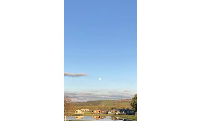 Lodges reflected in the lake, with the moon above